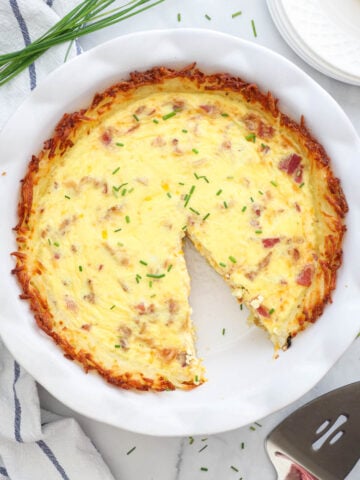 Quiche aux Pommes de Terre sur une assiette blanche avec un morceau manquant.