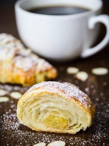 almond croissant sliced, accompanied by a cup of coffee