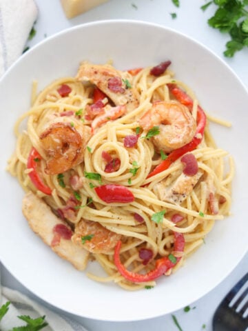 Poulet et Crevettes à la Carbonara sur une assiette blanche avec une fourchette à proximité