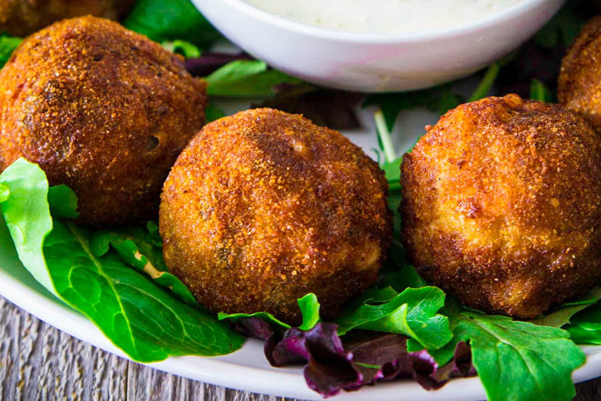 Croquettes de poulet sur un lit de laitue près d'un bol de sauce ranch.