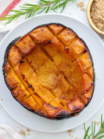 Half of a Roasted Acorn Squash on a white plate.