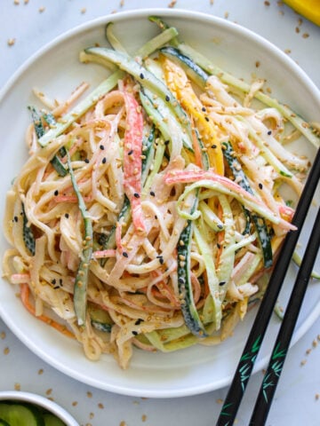 Image verticale de la salade Kani avec des baguettes sur le côté de l'assiette.