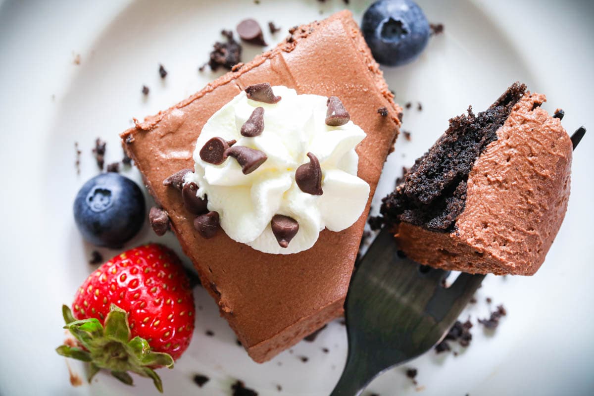 These easy and scrumptious no bake chocolate cheesecake bars are super quick to put together and require very little effort. They're so rich, creamy, and so indulgent! #chocolatecheesecake #nobakecheesecake #cheesecakebars #cheesecake #dessertbars No-bake Chocolate Cheesecake Bar with a forkful being lifted out.