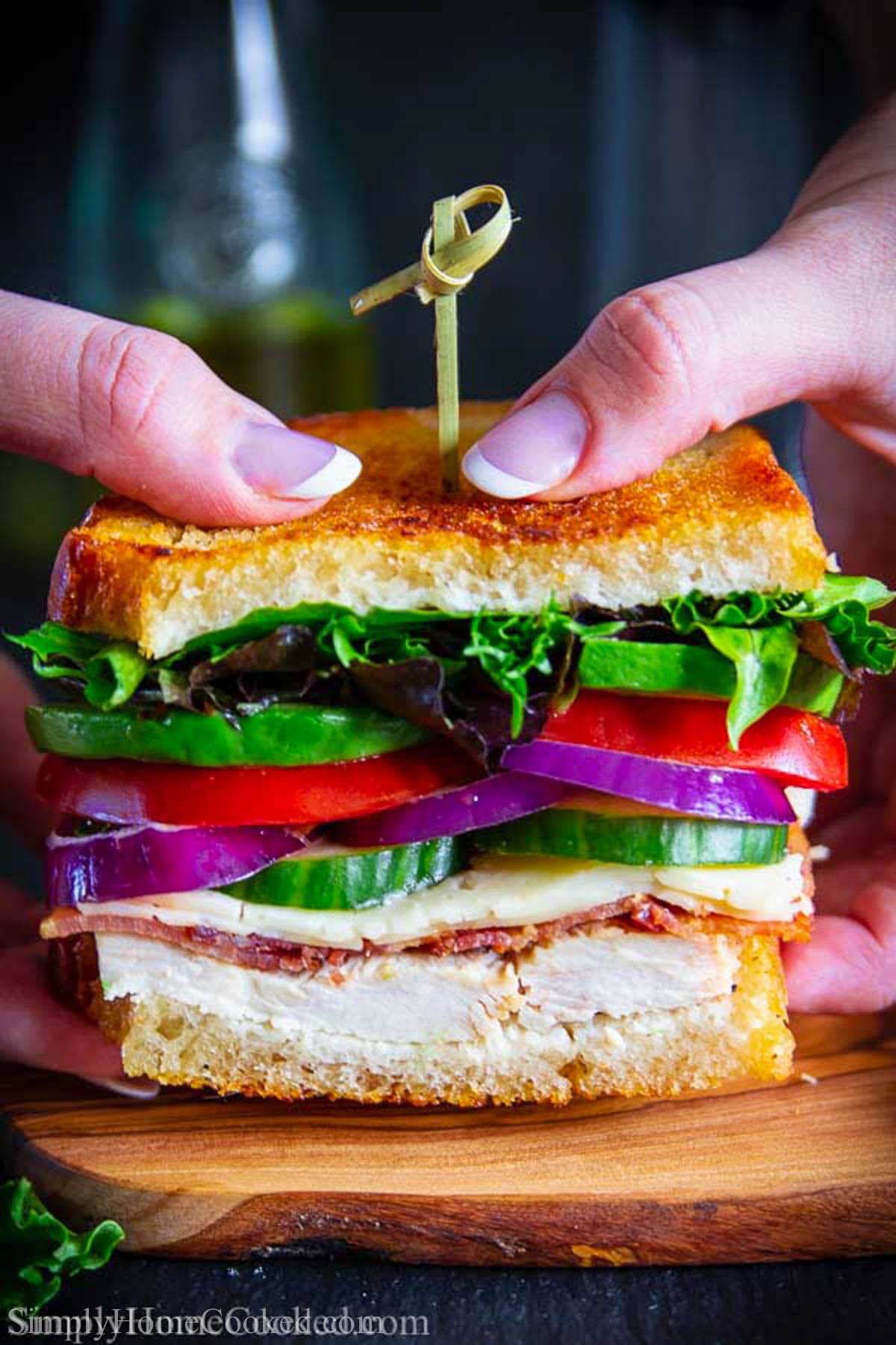 This leftover Turkey Sandwich is the ultimate way of enjoying every bit of those tasty Thanksgiving leftovers. This grilled sandwich is loaded with turkey, bacon, Havarti cheese, red onion, avocado, and tomatoes. #sandwich #turkeysandwich #leftoversandwich #turkeyleftoversandwich #thanksgivingsandwich Hands holding one half of a Turkey Melt.